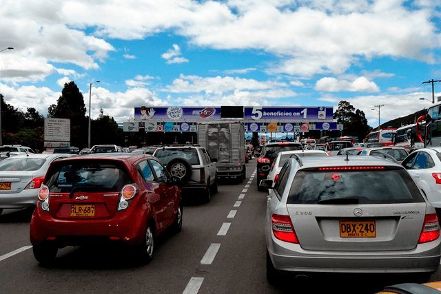Fila de carros en una vía de salida de la ciudad en un día soleado